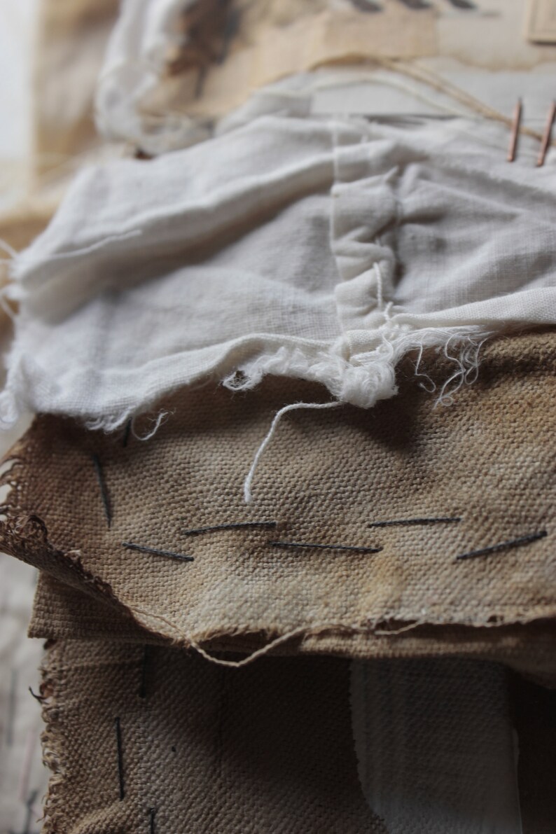 Puede incluir: Primer plano de una pila de recortes de tela, incluyendo una pieza blanca con un borde deshilachado y una pieza marr&oacute;n con costuras visibles. La tela es texturizada y tiene un aspecto r&uacute;stico.