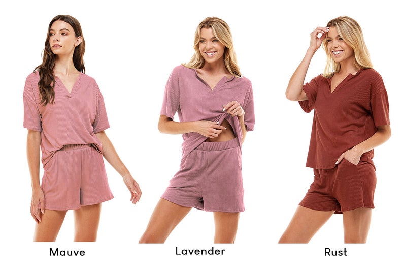 May include: Three women model matching short-sleeved tops and shorts sets in mauve, lavender, and rust colors. The sets are made of a soft, ribbed fabric.