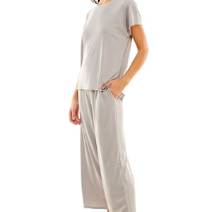 May include: A light grey ribbed knit top and matching wide-leg trousers. The top has a round neckline and short sleeves. The trousers have a wide waistband and pockets.