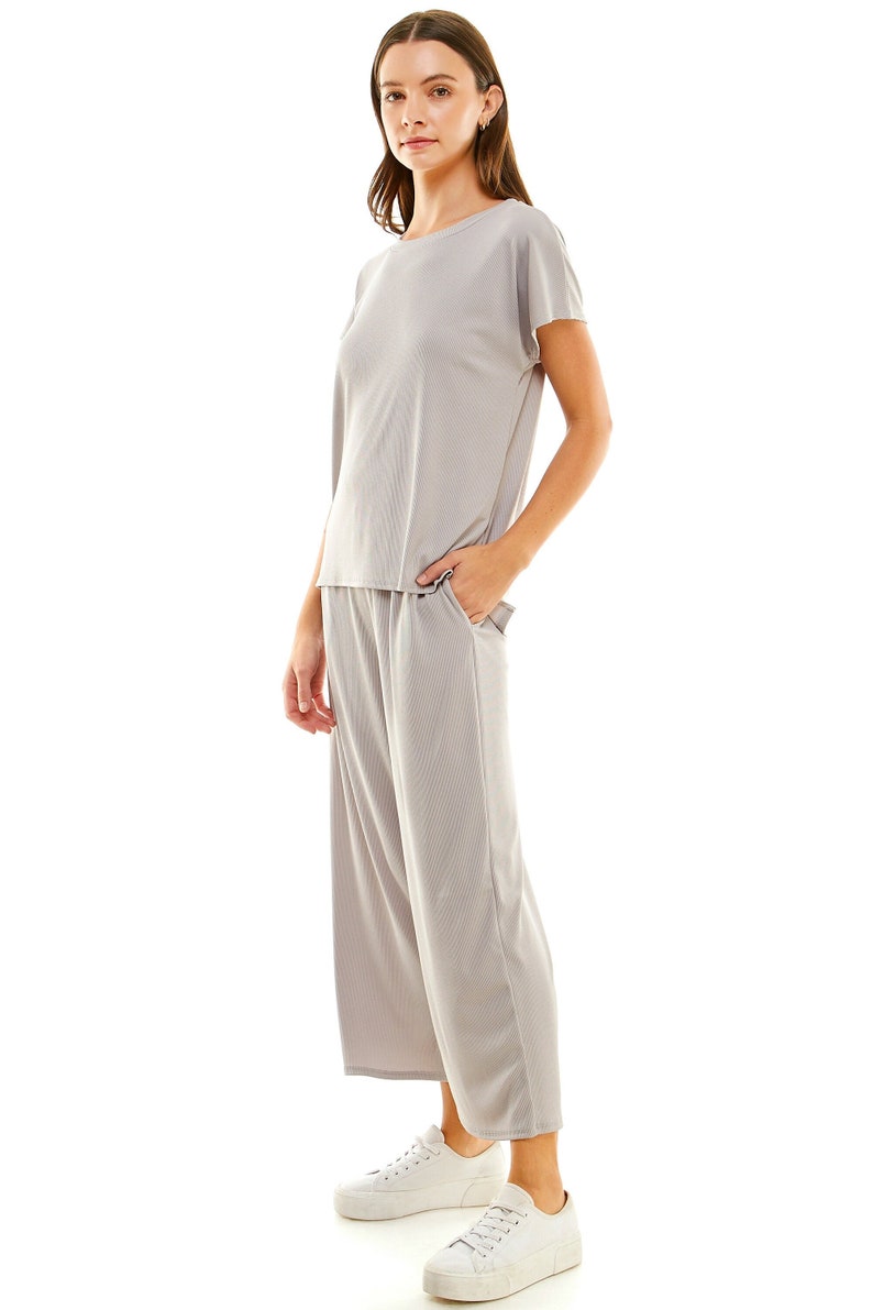 May include: A light grey ribbed knit top and matching wide-leg trousers. The top has a round neckline and short sleeves. The trousers have a wide waistband and pockets.