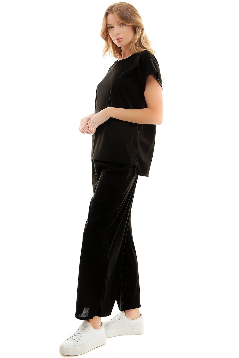 May include: A black velvet top and matching wide-leg trousers. The top has a round neckline and short sleeves. The trousers have a straight leg and a relaxed fit.