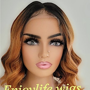 May include: A woman wearing a yellow shirt with a silver necklace and a brown and blonde bob wig. The wig has a lace front and is styled in loose waves. The text "Enjoylife Wigs" is visible at the bottom of the image.