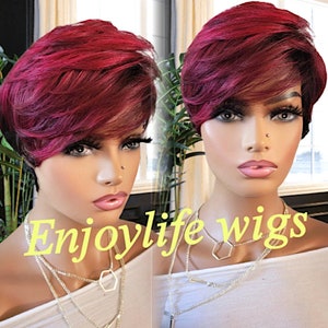 Può includere: Una parrucca corta di stile pixie, di colore bordeaux, con riga laterale e strati. La parrucca è acconciata con un'onda leggera e viene indossata da un manichino. Il testo "Enjoylife wigs" è visibile nell'immagine.