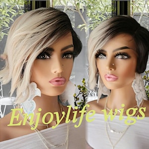May include: Two mannequins wearing short, black and blonde wigs with side bangs. The wigs are styled with a side part and have a layered look. The mannequins are wearing white shirts and silver necklaces. The text "Enjoylife Wigs" is printed in yellow at the bottom of the image.