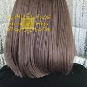 May include: A straight, shoulder-length wig in a light gray color. The wig is styled with a slight wave and has a natural-looking finish. The wig is displayed on a black mannequin head.