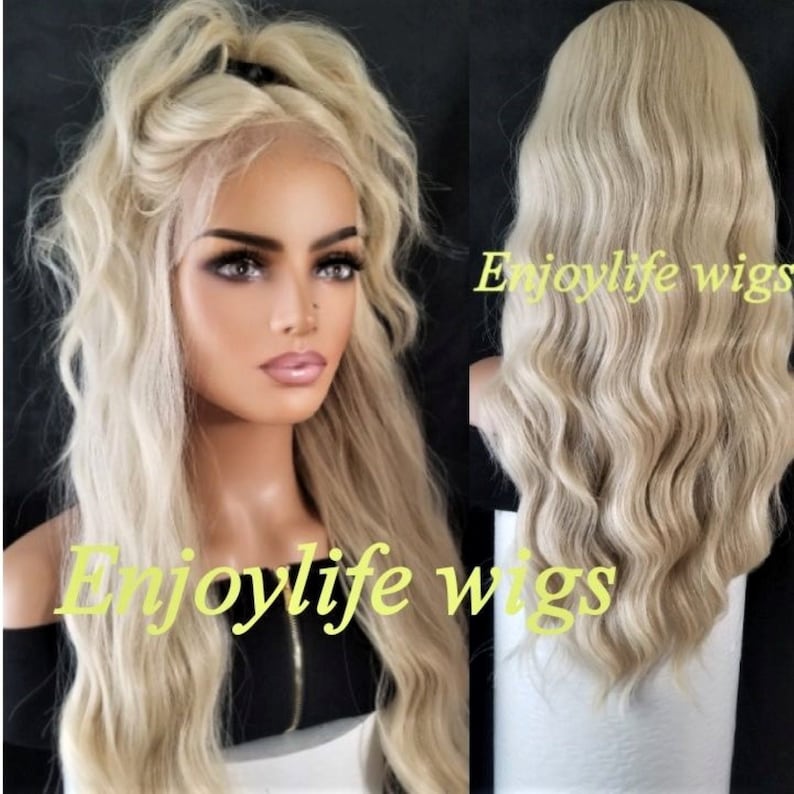 May include: A long, wavy, light blonde wig with a lace front. The wig is styled with loose waves and is worn by a model with a black top. The text "Enjoylife Wigs" is visible on the image.