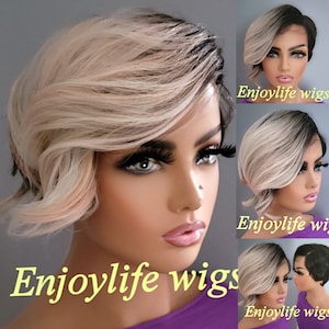 Peut inclure: Une perruque courte et ondulée, blonde avec des racines noires. La perruque est coiffée avec une raie sur le côté et a un aspect en couches. La perruque est portée par un mannequin avec une expression neutre. Le texte "Enjoylife wigs" est visible sur l'image.