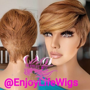 Könnte beinhalten: Eine kurze, stufige, blonde Perücke mit Seitenscheitel und Pony. Die Perücke ist im Pixie-Schnitt mit Schichten und einem strukturierten Finish gestylt. Die Perücke befindet sich auf einem Mannequin-Kopf mit blauem Hintergrund.