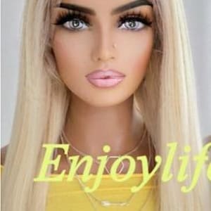 May include: A blonde wig with long, straight hair. The image features a person with full makeup, including dark eyebrows, long eyelashes, and pink lipstick. The person is wearing a yellow top and layered necklaces. The text "Enjoylife" is across the image.