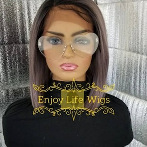 May include: A gray and black wig with a straight bob style. The wig is on a mannequin head wearing heart-shaped glasses. The text "Enjoy Life Wigs" is visible on the image.