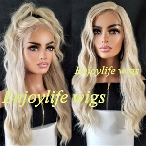 May include: Two blonde wigs with long, wavy hair. The wigs are styled in a side parting and have a natural, flowing look. The wigs are displayed on mannequins wearing black tops. The text "Enjoylife wigs" is visible on the image.