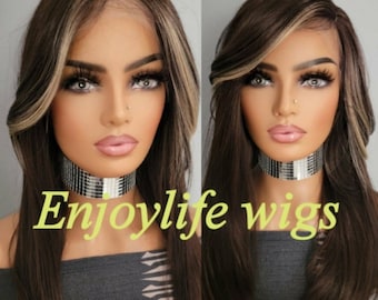 Może przedstawiać: Długa, prosta brązowa peruka z blond pasemkami. Peruka jest ułożona z przedziałkiem z boku i ma naturalnie wyglądającą linię włosów. Perukę nosi manekin z srebrnym chokerem. W obrazie widoczny jest tekst "Enjoylife wigs".