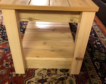 May include: A wooden coffee table with a natural finish and a lower shelf. The table is sitting on a patterned rug.