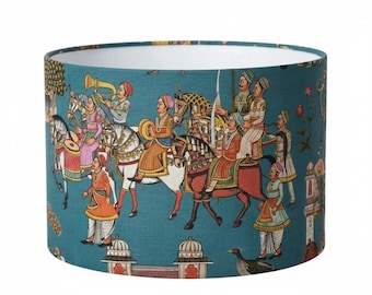 May include: Teal lampshade featuring a detailed illustration of a royal procession with figures on horseback, musicians, and architectural elements. The design includes vibrant colors and intricate patterns, creating a decorative and cultural aesthetic.