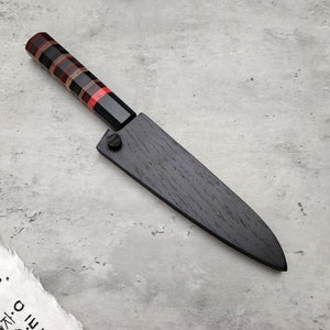 Puede incluir: Un cuchillo de cocina de madera negra con mango de madera roja, negra y marr&oacute;n.