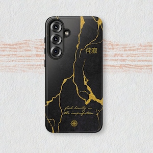 May include: Black phone case with a gold vein design and the text "find beauty in the imperfection." The case has a camera module on the upper left side and a gold compass symbol.