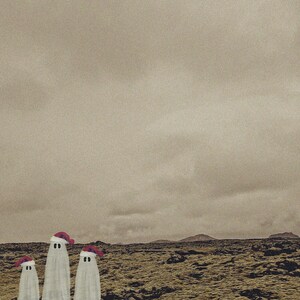 May include: Three white ghosts wearing red Santa hats stand in a barren, rocky landscape. The sky is overcast and gray.