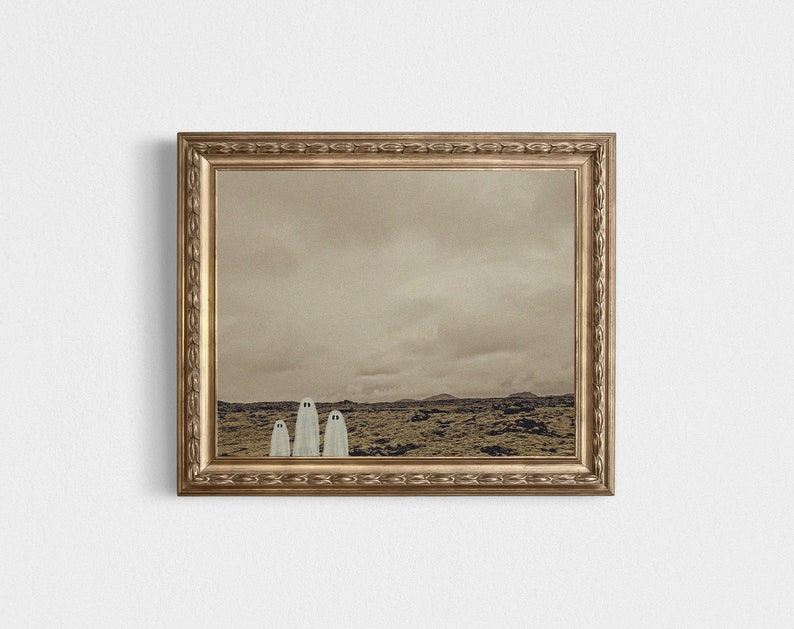 May include: A framed print of a sepia-toned landscape with three white ghost figures standing in a row in the foreground.