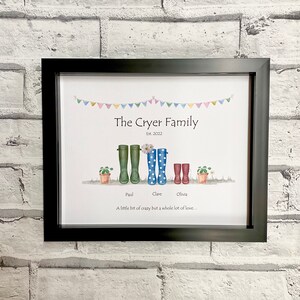 May include: A framed print with a watercolor illustration of a family of four wearing colorful rain boots. The text reads "The Cryer Family Est. 2022" and "A little bit of crazy but a whole lot of love..."