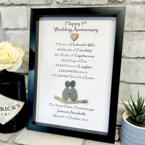 Può includere: Una stampa incorniciata con sfondo bianco e cornice nera. La stampa presenta un design in ciottoli di una coppia che si abbraccia, insieme al testo "Happy 5th Wedding Anniversary" e un elenco di pietre miliari nella loro relazione, tra cui "5 Years as Husband & Wife", "60 Months of Friendship", "261 Weeks of Togetherness", "1826 Days of Fun", "43,824 Hours of Laughter", "2,629,440 Minutes & 157,766,400 Seconds of Love..." e "Five Years Down...Forever to go! James & Annabelle Married 1st October 2019".