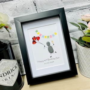 May include: A framed pebble art picture with a gray figure holding red balloons and a glass of champagne. The picture says "Happy 40th Birthday Sue 01/07/2024".