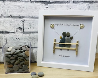 May include: A white framed picture with a pebble art design of a couple sitting on a bench with two balloons. The text reads "Happy 30th Wedding Anniversary" and "Wilbo & Katrina".