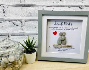 May include: A framed pebble art piece with a gray frame and a white background. The art features two figures made of pebbles, a red heart, and a small piece of driftwood. The text reads "Soul Mate is someone who will always love, understand and be there for you no matter what... You & me forever, love you more each day. We will be forever XXX Love you John."