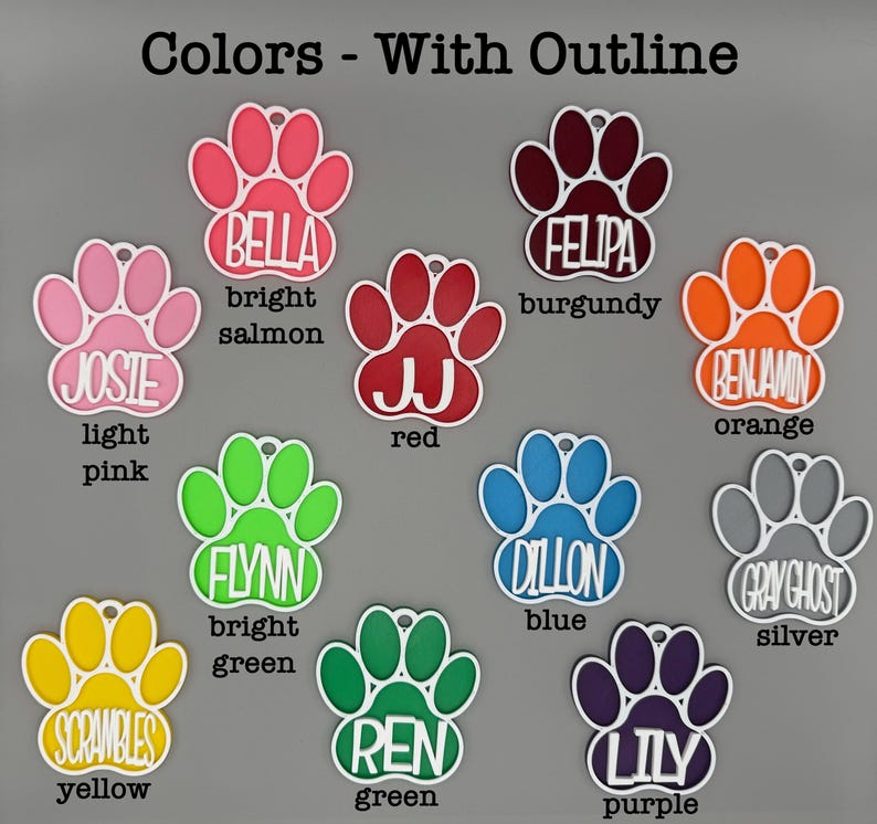 May include: A selection of colourful paw-shaped pet tags, each with a name and colour. The tags feature names such as "Bella" (bright salmon), "Josie" (light pink), and "Scrambles" (yellow). Each tag has a white outline and a hole for attachment.