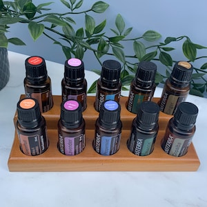 May include: A wooden essential oil rack with 10 amber glass bottles. The bottles are labelled with the brand name "dōTERRA" and the names of the essential oils: Grapefruit, Lavender, Peppermint, Balance, Copaiba, Ginger, Eucalyptus, Pepper-mint, Lemon, and  "dōTERRA" Active.