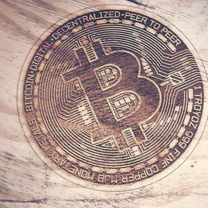 May include: A close-up of a wooden coin with a Bitcoin logo and the text "BITCOIN DIGITAL DECENTRALIZED - PEER TO PEER - 1 TROYOZ 999 FINE COPPER MLB MONEY PAYALS".