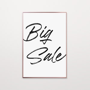 Könnte beinhalten: Gerahmter Druck mit den Worten "Big Sale" in schwarzer Pinselschrift auf weißem Hintergrund. Der Rahmen ist aus dünnem, kupferfarbenem Metall. Das Kunstwerk ist schlicht und modern, geeignet für die Wohn- oder Bürodekoration.