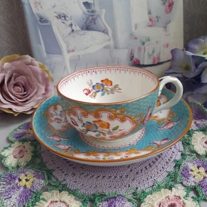 May include: A vintage teacup and saucer set with a blue and white floral pattern. The cup and saucer have a gold trim and are decorated with delicate floral designs.