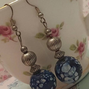 May include: A pair of dangle earrings with blue and white marbled glass beads and silver metal accents.