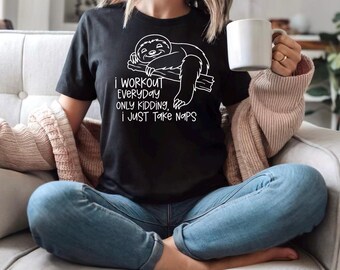 May include: Black t-shirt with a white graphic of a sleeping sloth on a branch and the text "I WORKOUT EVERYDAY ONLY KIDDING, I JUST TAKE NAPS." The person is wearing blue jeans and holding a white mug.