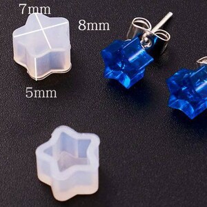 May include: Two pairs of star-shaped earring findings. One pair is clear and the other is blue. The clear findings are 7mm wide and 5mm tall. The blue findings are 8mm wide.