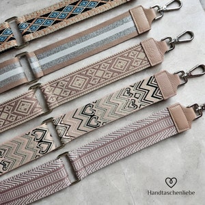 May include: Five different patterned fabric straps with leather ends and metal clasps. The straps are in shades of beige, pink, and brown. The straps are all different patterns, including geometric, floral, and chevron.