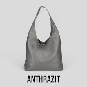 May include: A grey leather hobo bag with a single strap. The bag has a slouchy, casual look. ANTHRAZIT is written in black text below the bag.