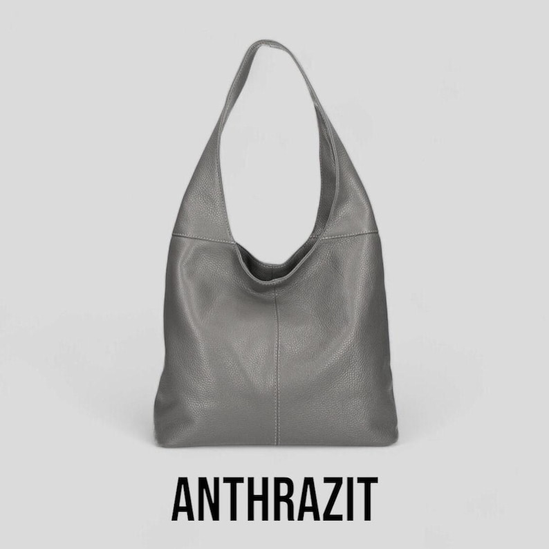 May include: A grey leather hobo bag with a single strap. The bag has a slouchy, casual look. ANTHRAZIT is written in black text below the bag.