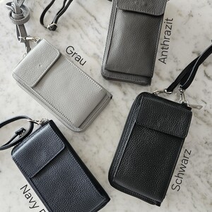 May include: Four leather crossbody phone bags in gray, anthracite, navy blue, and black. Each bag has a flap closure, a zippered main compartment, and a detachable strap. The bags are displayed on a marble surface.