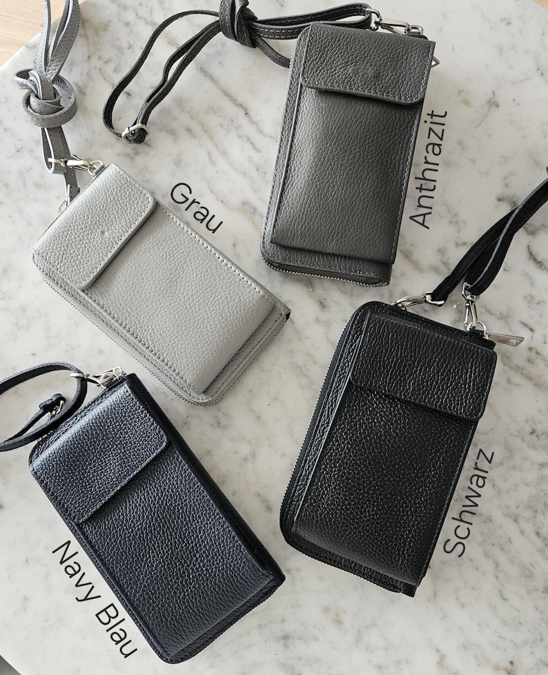 May include: Four leather crossbody phone bags in gray, anthracite, navy blue, and black. Each bag has a flap closure, a zippered main compartment, and a detachable strap. The bags are displayed on a marble surface.