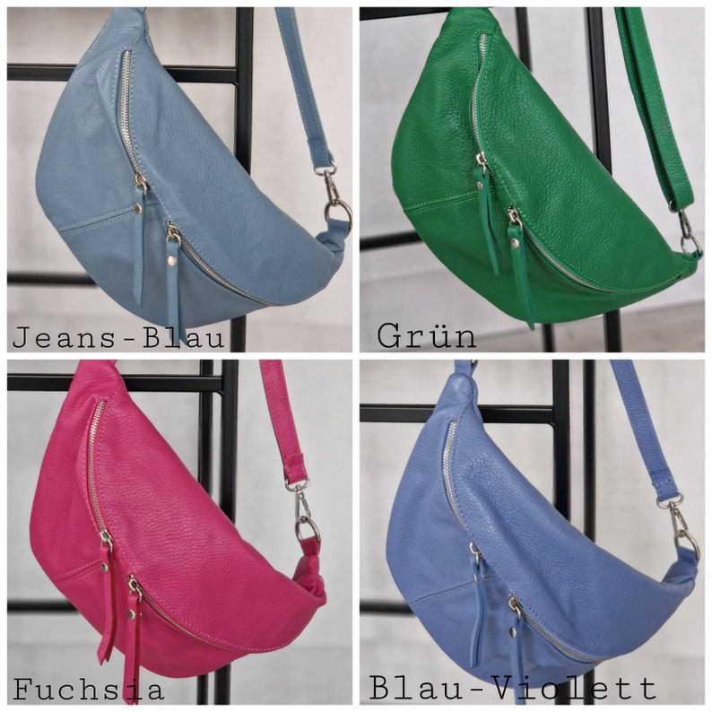 Op de afbeelding: Vier leren heuptassen in verschillende kleuren: jeansblauw, groen, fuchsia en blauw-violet. Elke tas heeft een gebogen vorm, een ritssluiting en een verstelbare riem. De tassen worden gepresenteerd tegen een zwart metalen rek.