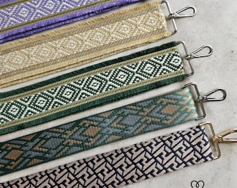 May include: Five different woven fabric straps with metal clasps. The straps have various geometric patterns in shades of green, beige, black, and purple.