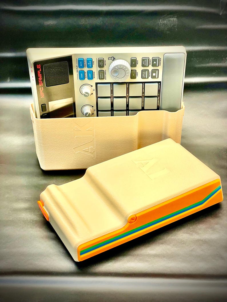 May include: A beige MPC Sample music production device with a matching case. The device has various buttons, knobs, and a screen. The case has a colorful stripe design with orange, blue, and green accents. The text "MPC SAMPLE" is visible.