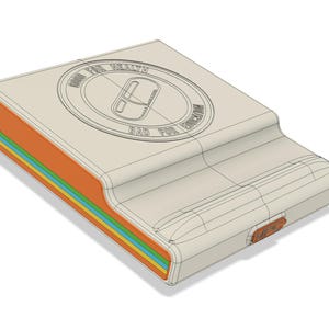 May include: A beige, rectangular device with a curved top and a colorful side panel. The side panel features orange, green, blue, and yellow stripes. The top has a circular design with the text "GOOD FOR HEALTH" and "BAD FOR EDUCATION".