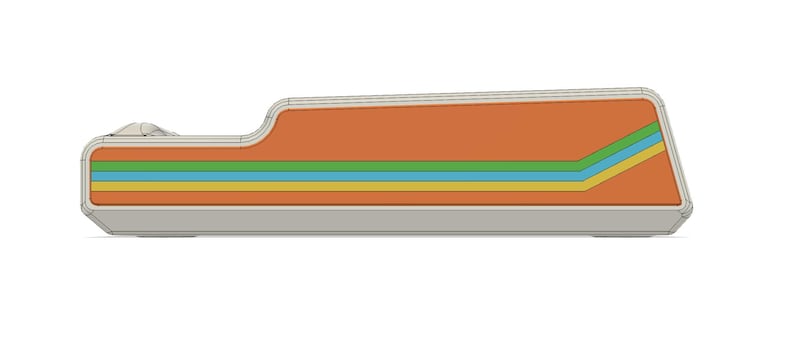 May include: A retro-style, rectangular device with an orange top and a gray base. The design features horizontal stripes in green, yellow, and blue. The device has a curved edge on one side and a slanted edge on the other.