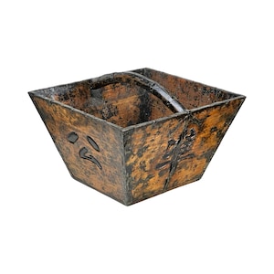 May include: A square, wooden bucket with a dark brown finish and a curved handle. The bucket has black accents and Japanese characters carved into the side. The handle is made of a dark, possibly metal, material.