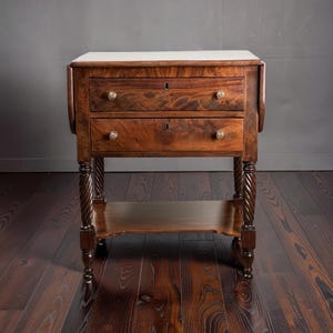 May include: A two-drawer antique side table with a white top and dark wood finish. The drawers have brass knobs and keyholes. The table features carved, spiral-turned legs and a lower shelf. A classic piece of furniture.