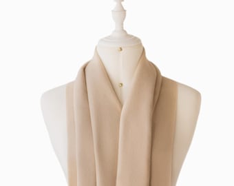 May include: A beige cashmere scarf with fringed edges. The scarf is draped over a white mannequin.