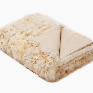 May include: A soft, cream-colored faux fur throw blanket with a smooth, cream-colored underside.