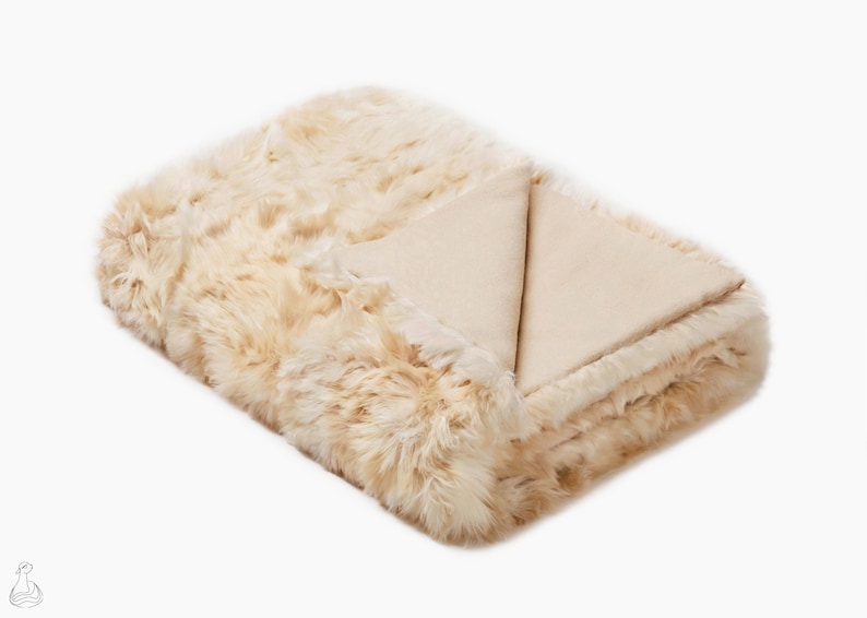 May include: A soft, cream-colored faux fur throw blanket with a smooth, cream-colored underside.